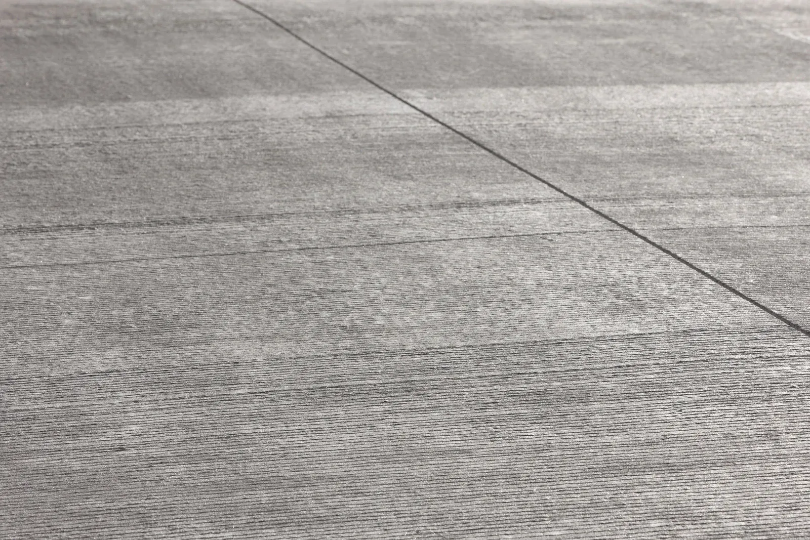 Gray pavement with wave-like patterns and a single line, possibly a road.