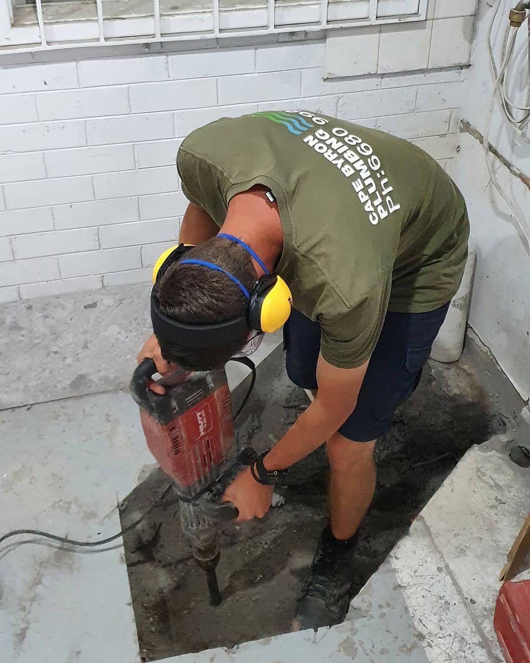A man is drilling into the ground to do plumbing work.