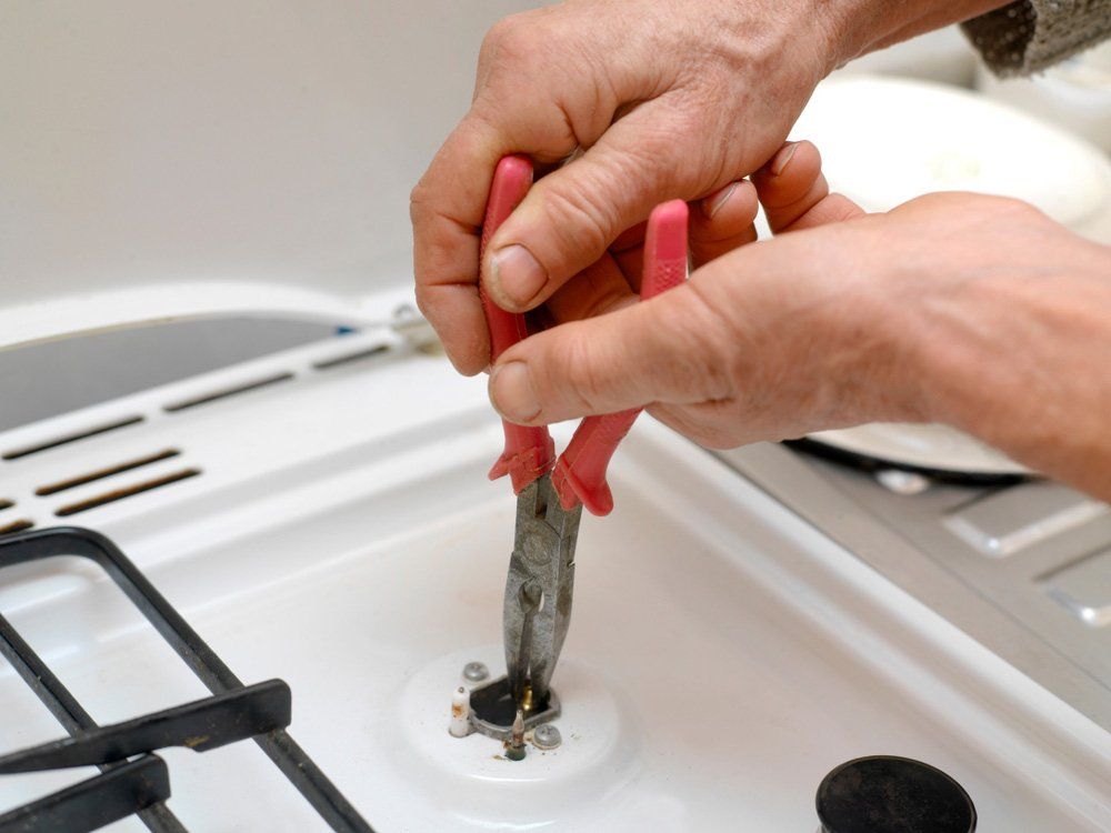 Man Repairing A Gas Stove — Cape Byron Plumbing in Byron Bay, NSW