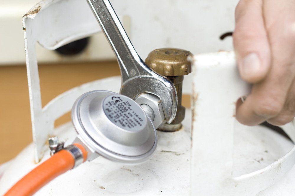 A Person is Fixing a Propane Tank With a Wrench — Cape Byron Plumbing in Alstonville, NSW