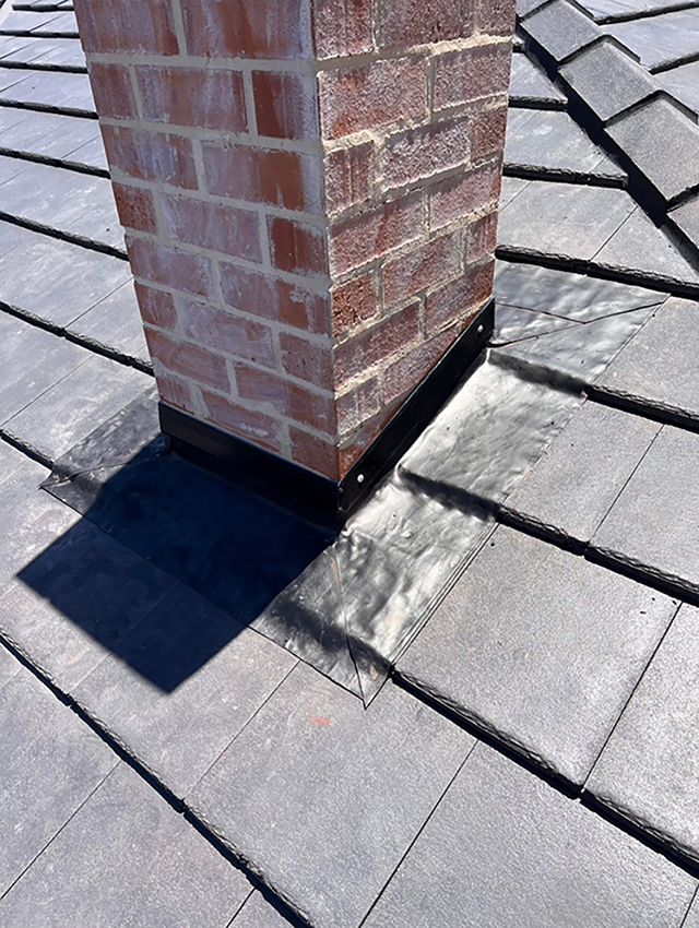 A Brick Chimney is Sitting on Top of a Tiled Roof — Boss Roof Tiling and Restoration in Caboolture, QLD