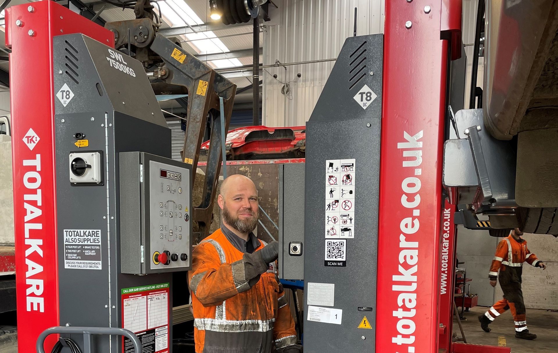 HGV fitter operating vehicle lifts in busy workshop