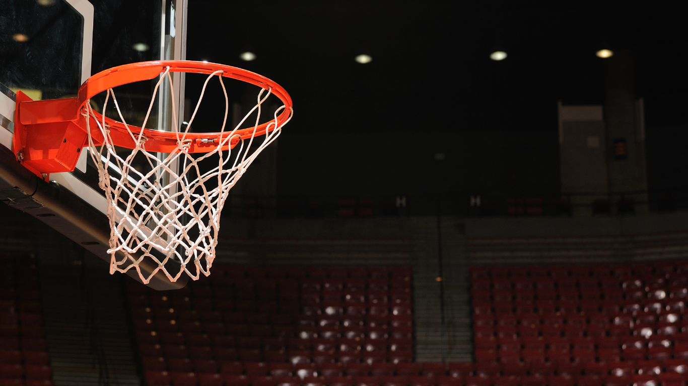 A man with a broken arm is standing next to a basketball hoop.