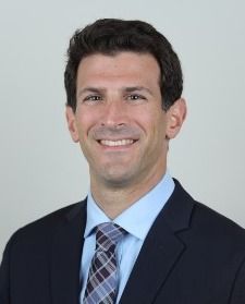 A man in a suit and tie is smiling for the camera.