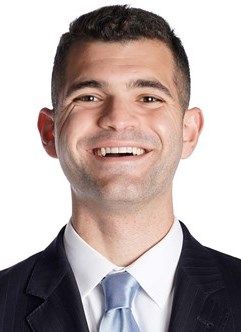 A man in a suit and tie is smiling for the camera.