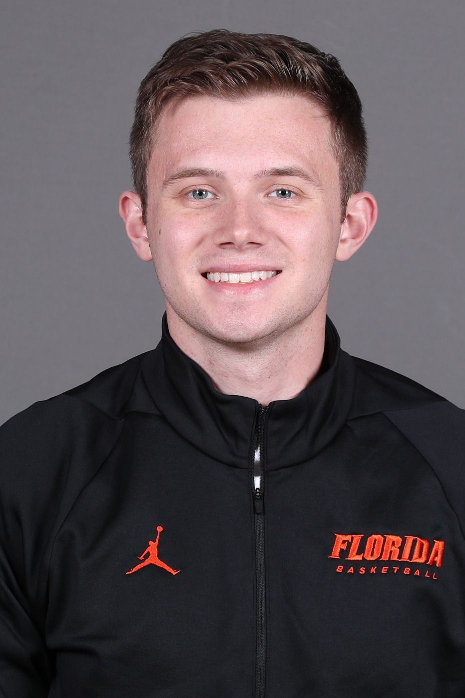 A young man wearing a florida jacket is smiling for the camera.