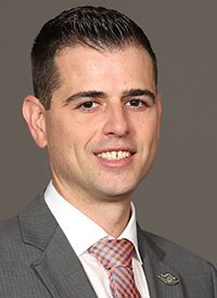 A man in a suit and tie is smiling for the camera.