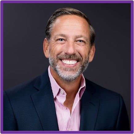A man with a beard and a suit is smiling for the camera.