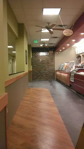 A long hallway in a restaurant with wooden floors and a ceiling fan.