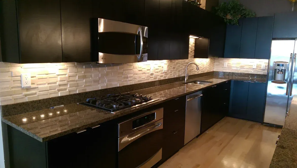 A kitchen with black cabinets and stainless steel appliances