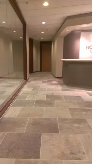 A long hallway with a tiled floor and a reception desk.
