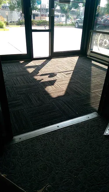 A doorway with a mat on the floor and a shadow on the door.