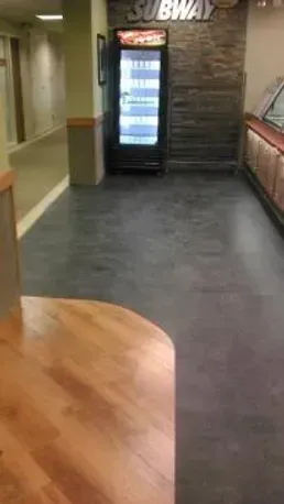 A subway restaurant with a refrigerator in the middle of the room.