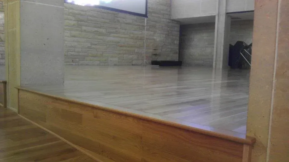A large empty room with a wooden floor and a projector screen.