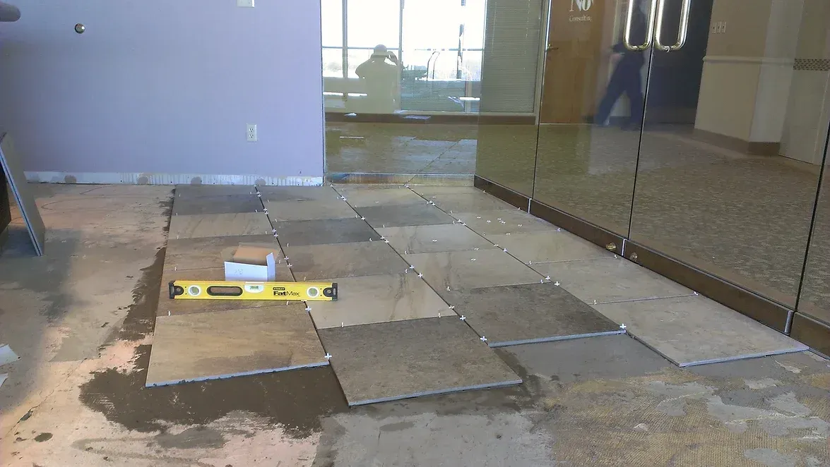 A yellow level is sitting on a tiled floor in a room.