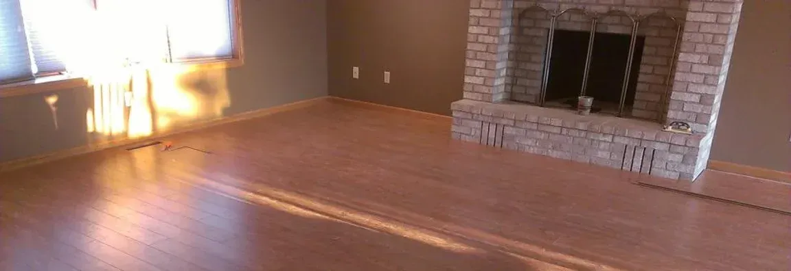An empty living room with a fireplace and hardwood floors.