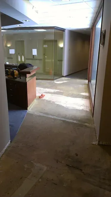 A hallway in a building with a desk and chairs in it.