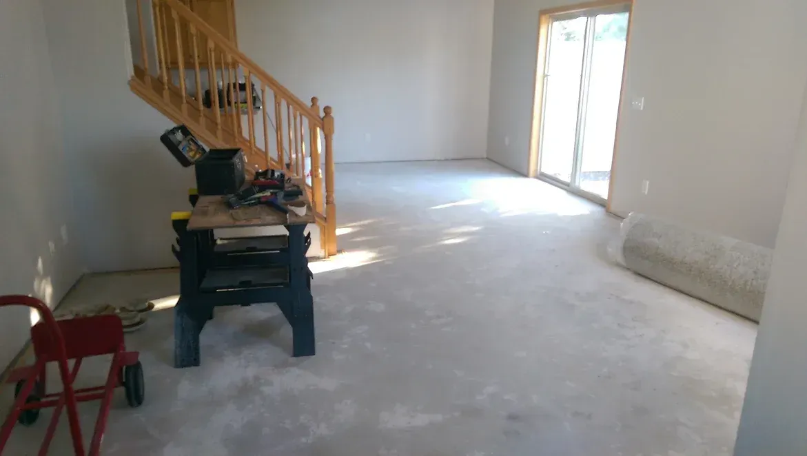 A room with a staircase and a workbench in it.