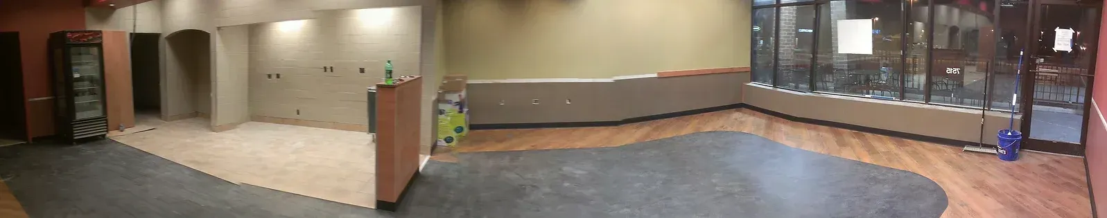 A large empty room with hardwood floors and a refrigerator.