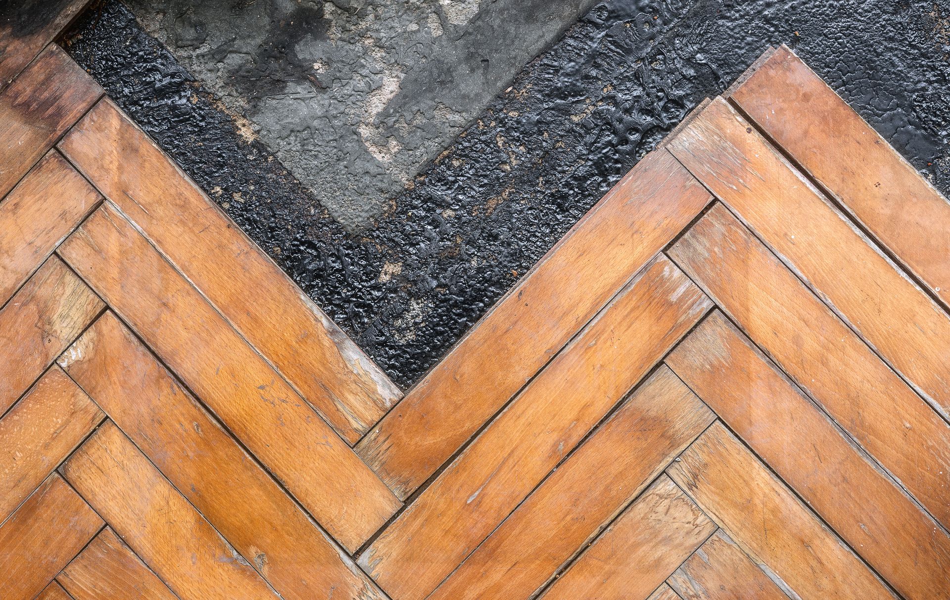 A close up of a wooden floor with a herringbone pattern.