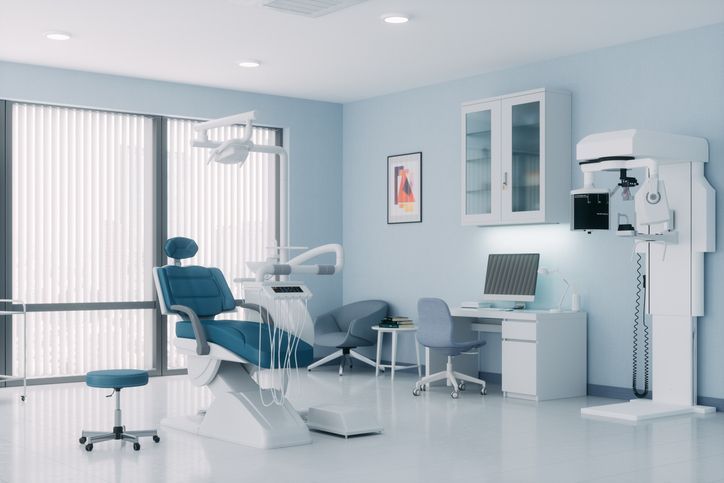 A dental office with a dental chair and a computer.