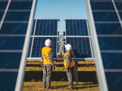 Two men are standing in front of a solar panel.