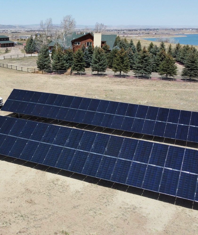 A row of solar panels in a field with trees in the background