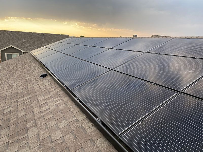 There are many solar panels on the roof of a house.
