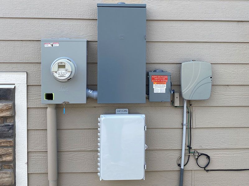 There are a lot of electrical boxes on the side of a house.