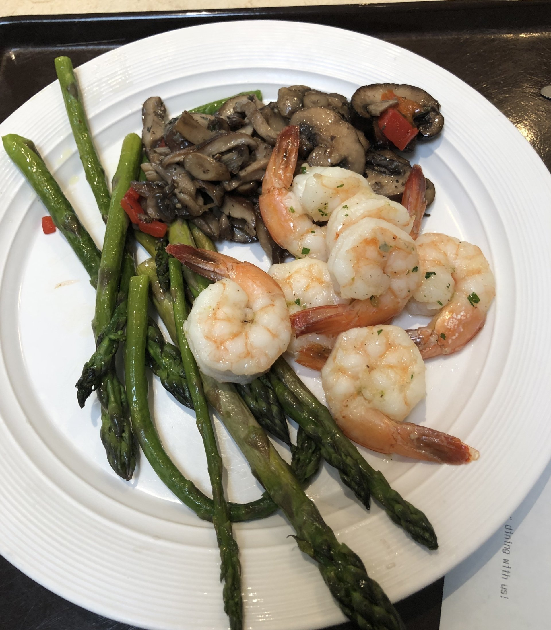 White plate with shrimp, asparagus, and sautéed mushrooms.
