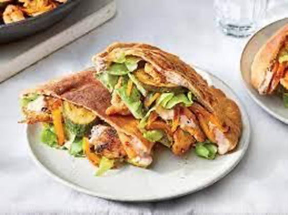 Pita bread halves filled with grilled vegetables and lettuce, on a white plate.
