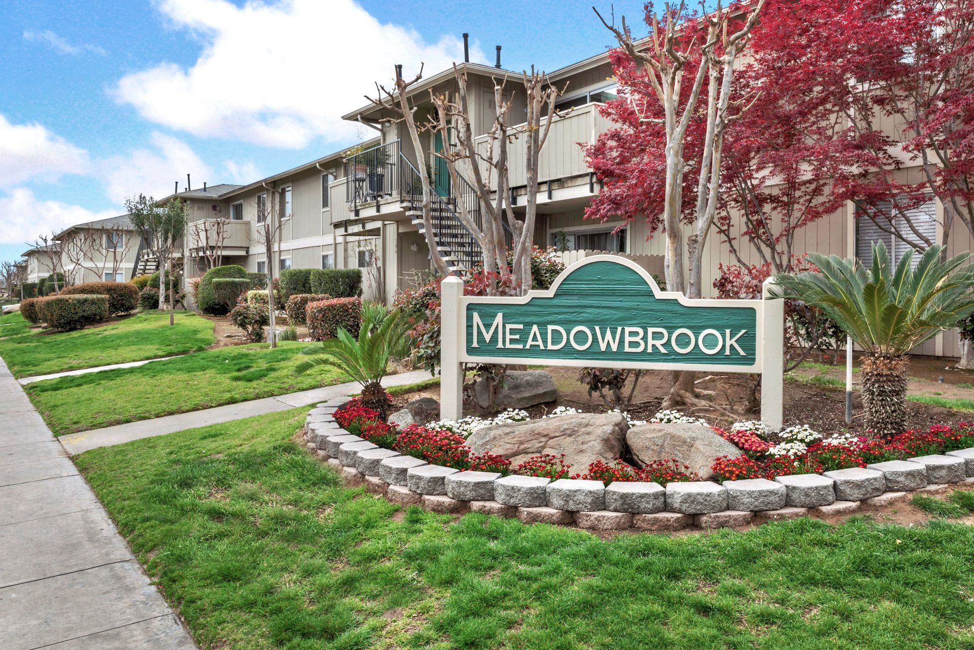 Meadowbrook apartment complex sign with building and landscaping.