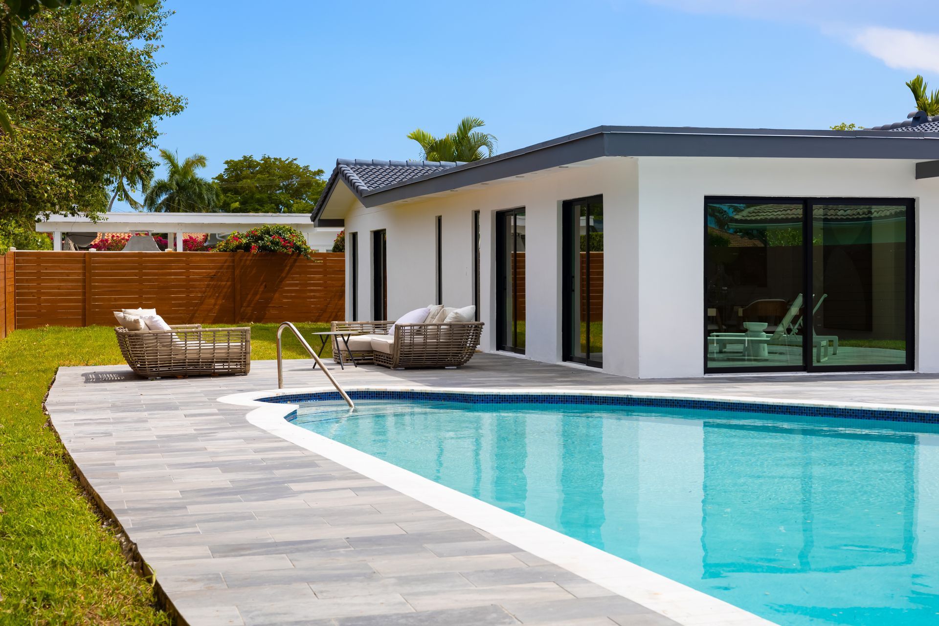 There is a large swimming pool in the backyard of a house.