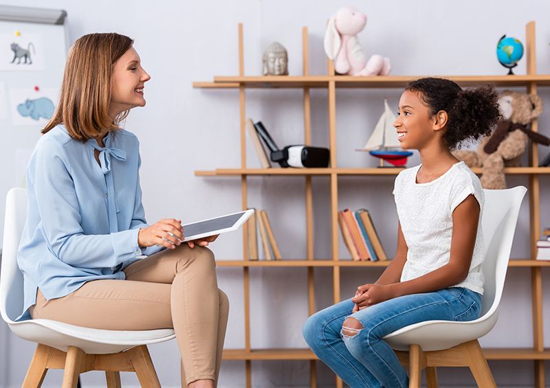 Woman with tablet talks to a girl in an office setting.