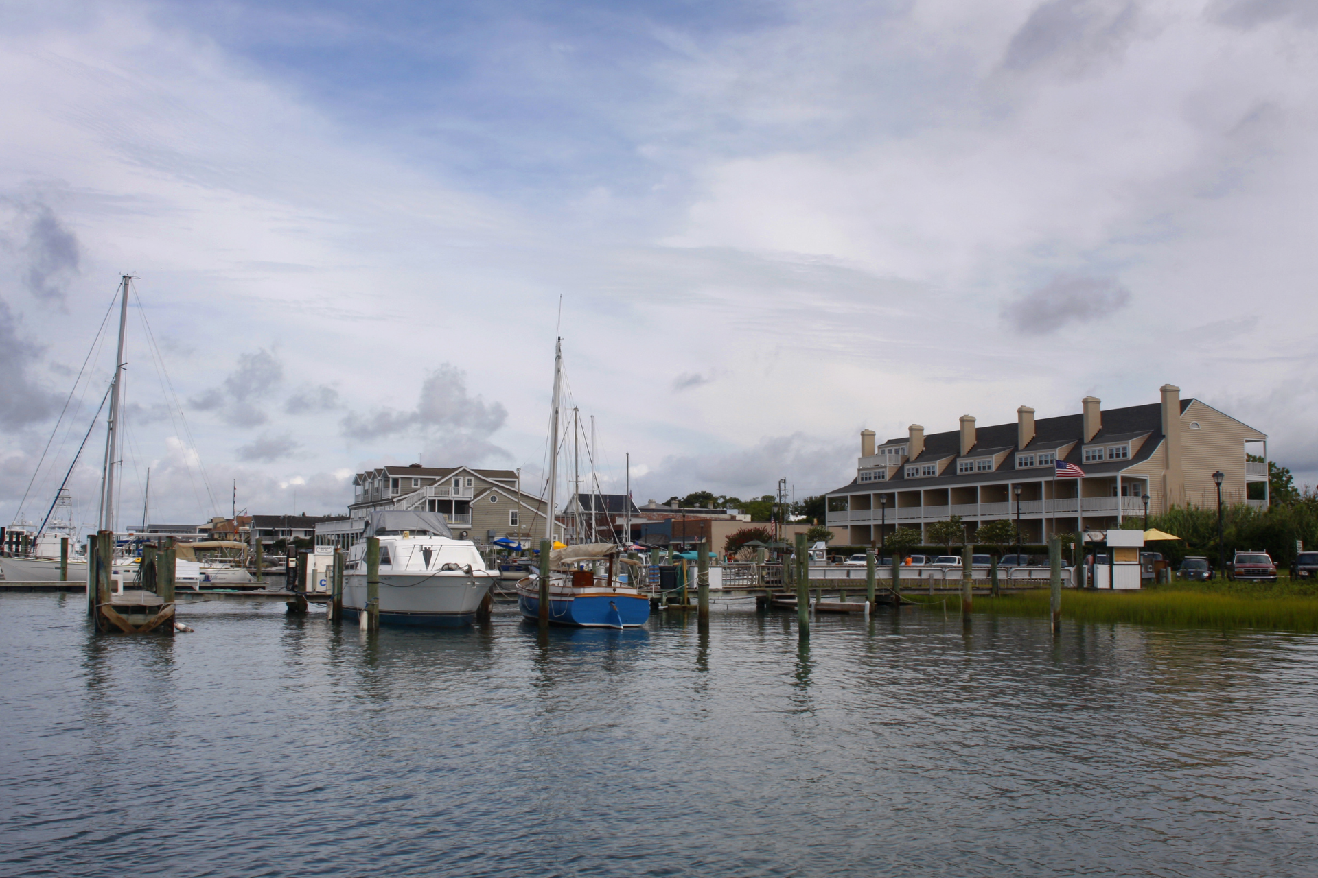 A large white plantation-style house with columns, partially obscured by trees with Spanish moss.