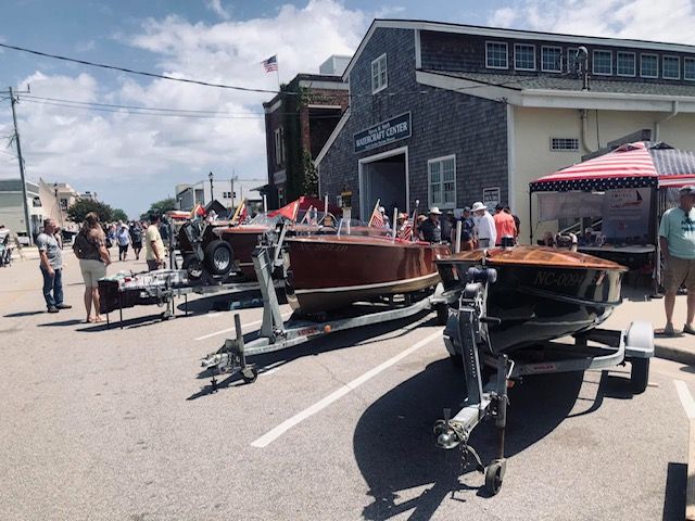 Restaurant with outdoor seating, waterfront view.  American flag waves. White fence, water, building with balconies.
