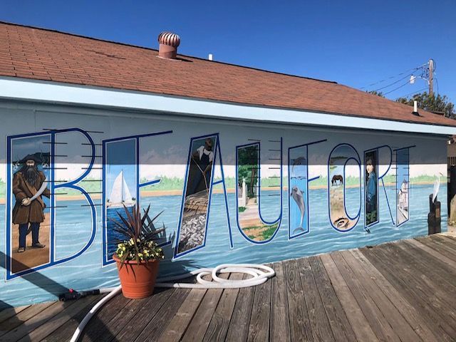 Sunset over ocean with pier; orange sky, foamy water.