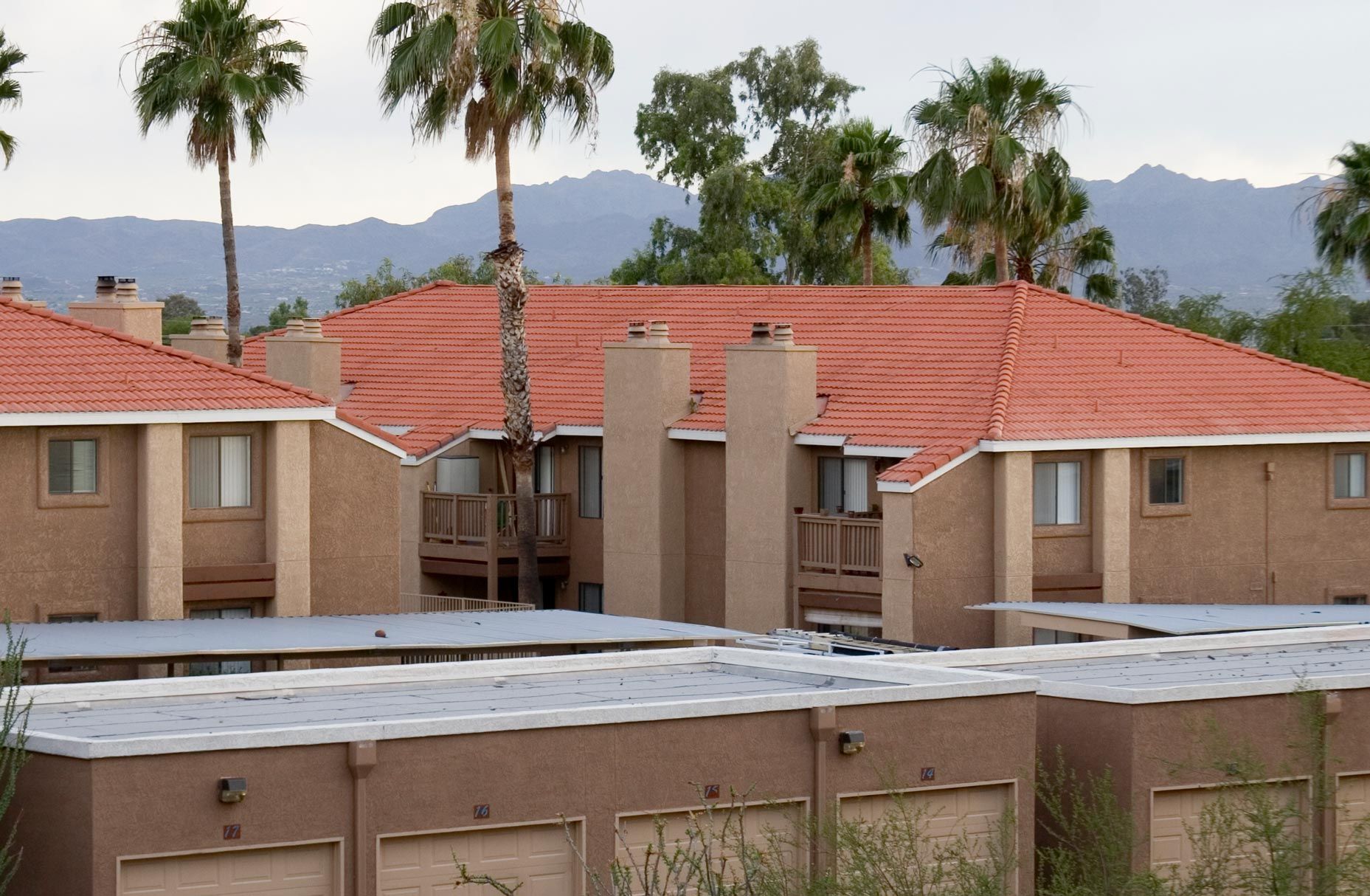 A building with a red tile roof and palm trees in the background