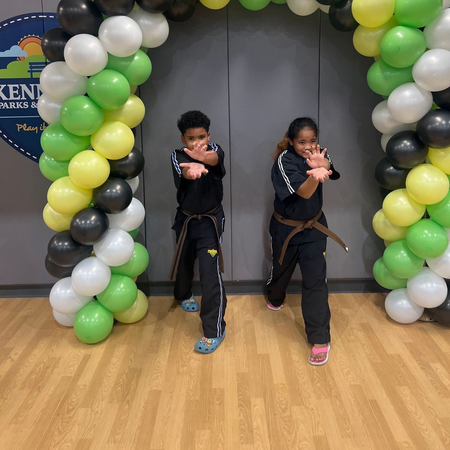 A group of children are practicing karate with a teacher in a gym.