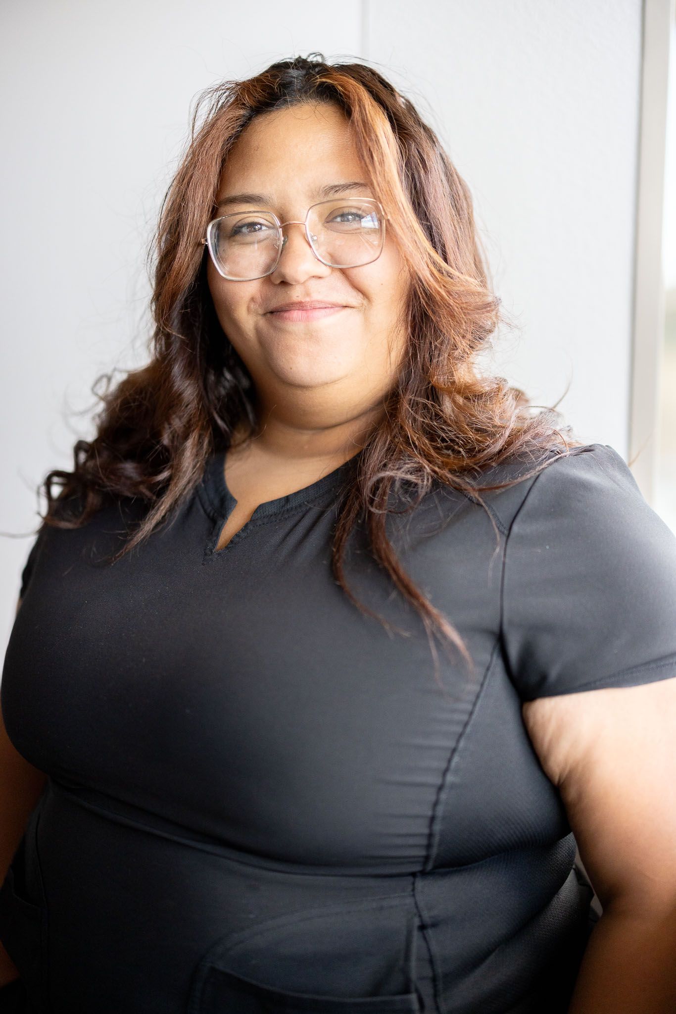 Norma who works the front desk is in a black scrub top is smiling camera. 