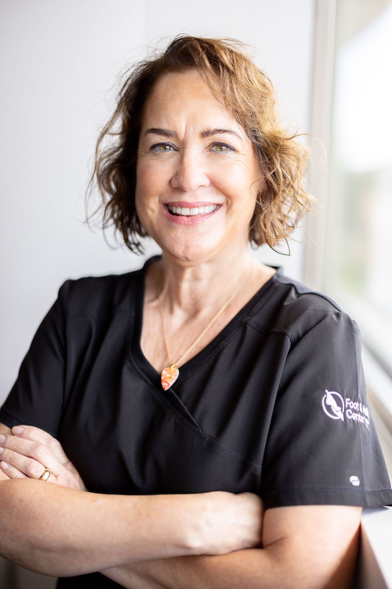 Erin who works the front desk is in a black scrub top is smiling for the camera.