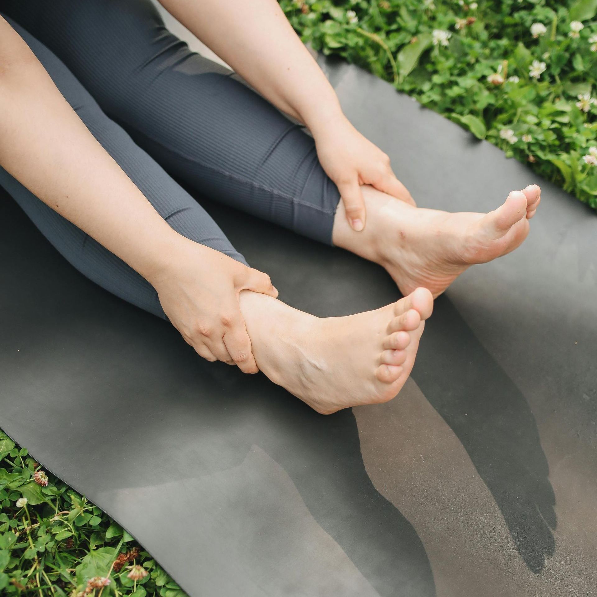 A woman is sitting on a yoga mat with her legs crossed