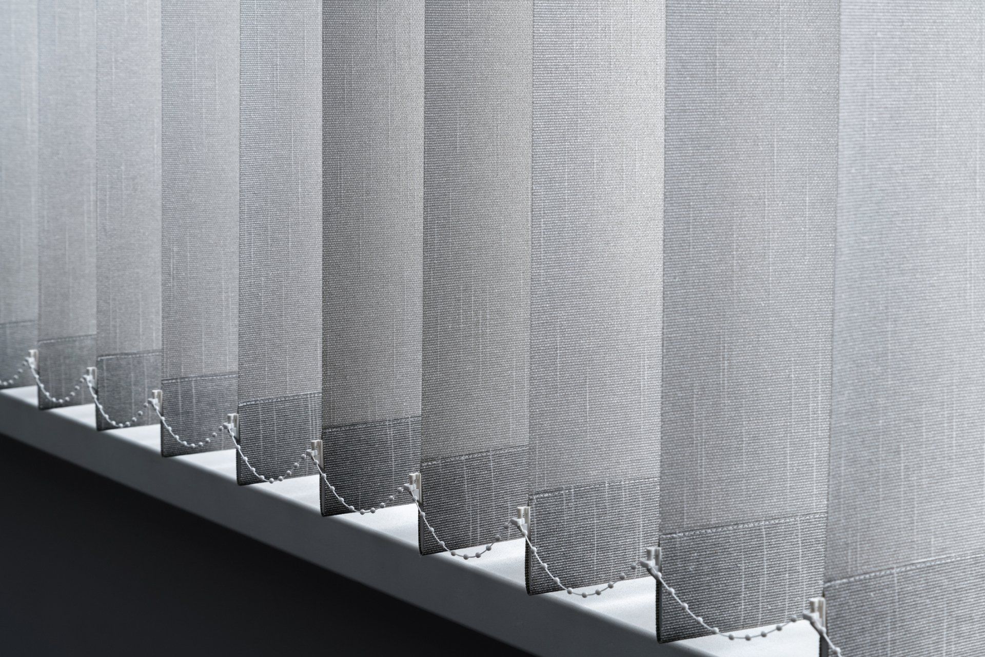 Vertical blinds, light gray, partially open, casting shadows.