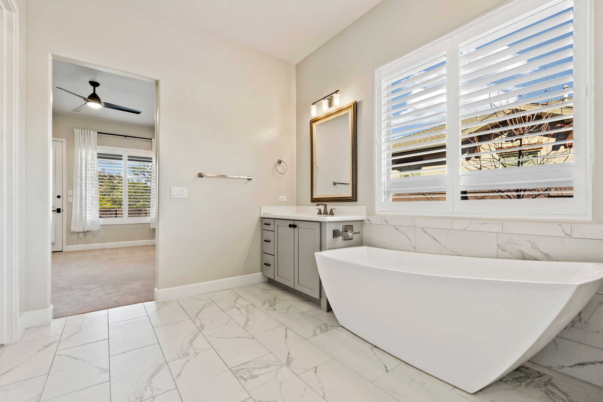 Elegant bathroom with marble featuring a freestanding tub and plantation shutters. Elegant bathroom with marble featuring a freestanding tub and plantation shutters.