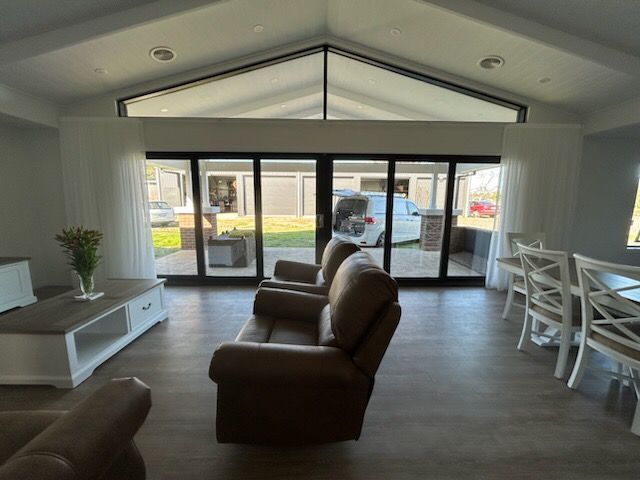 Living room with brown recliners, white table, and large glass doors overlooking a backyard.