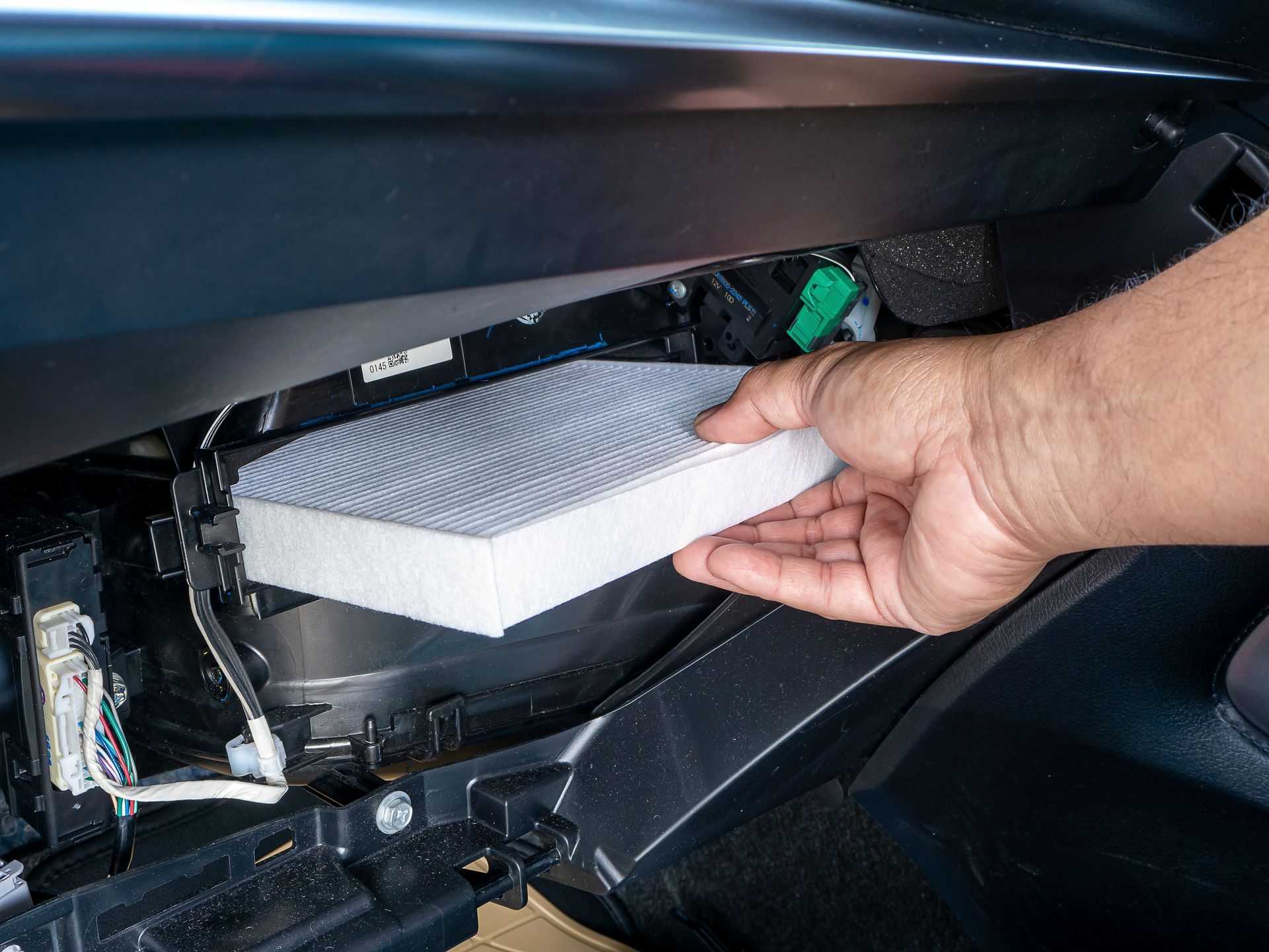 A person is holding a air filter in their hand in a car.