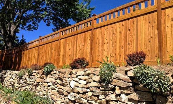 A wooden fence surrounds a rock wall.