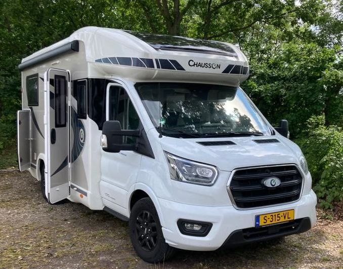 Geparkeerde Chausson camper op gras in een groene omgeving.