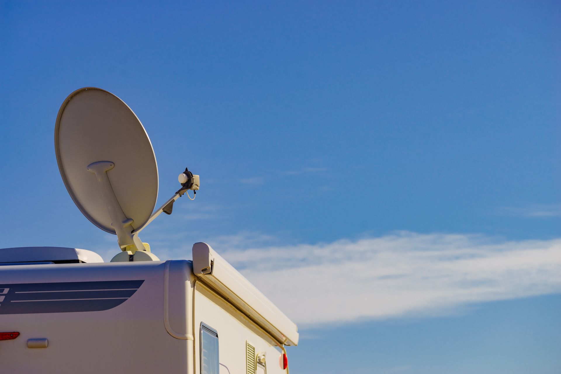 White RV with satellite dish against a blue sky.