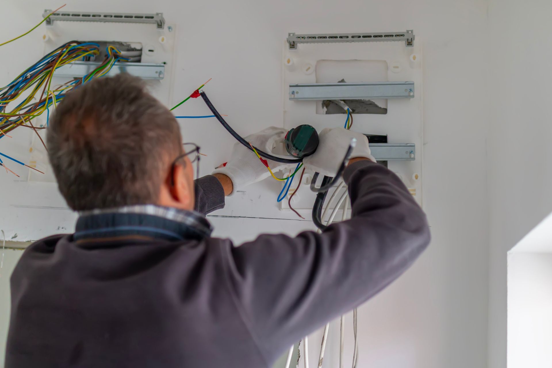 Electrician working on exposed wiring inside a wall.